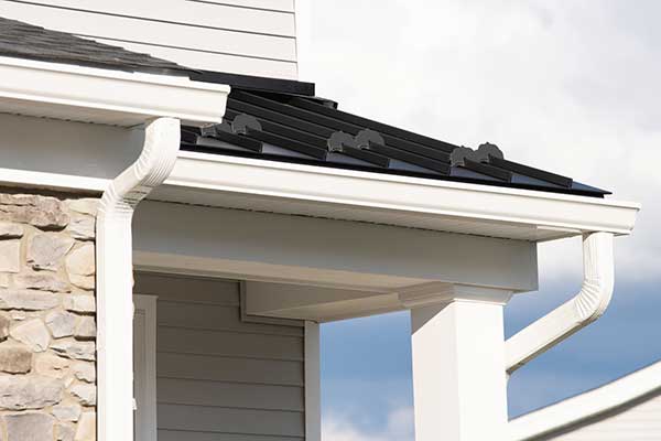Close up of white, k-style gutter systems on the fascia of a house with downspouts