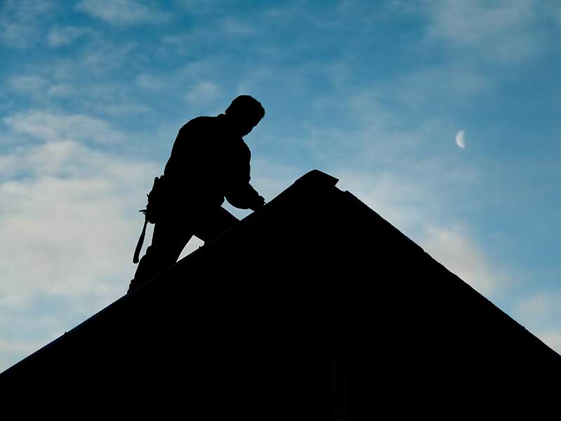 Silhouette of someone working on a residential rooftop