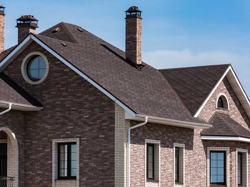 Mid-class, two-story home with brick siding and brown shingles